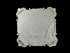A cream-colored napkin with Nottingham Guipure Lace trim, surrounded by a lace border.